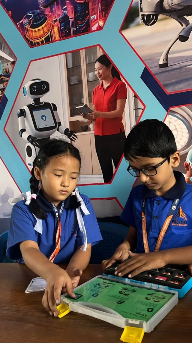 Two students place components onto an electronics kit board