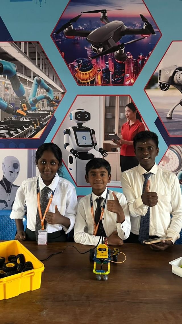 A team of three students poses with the small wheeled robot they built
