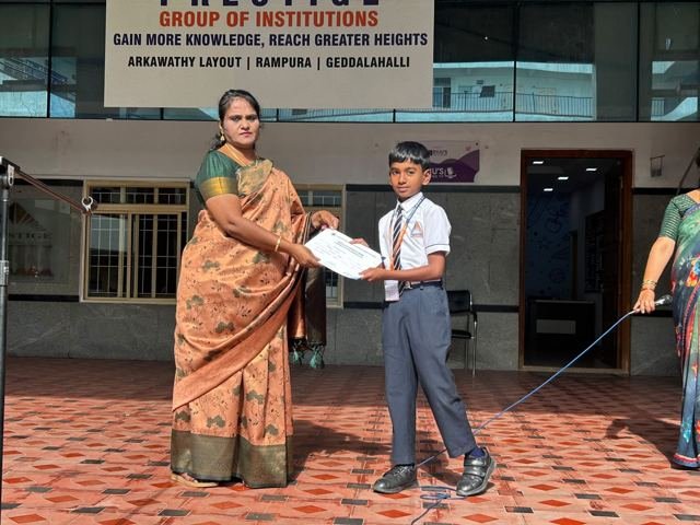 A teacher presents a certificate to a student on stage at a school event