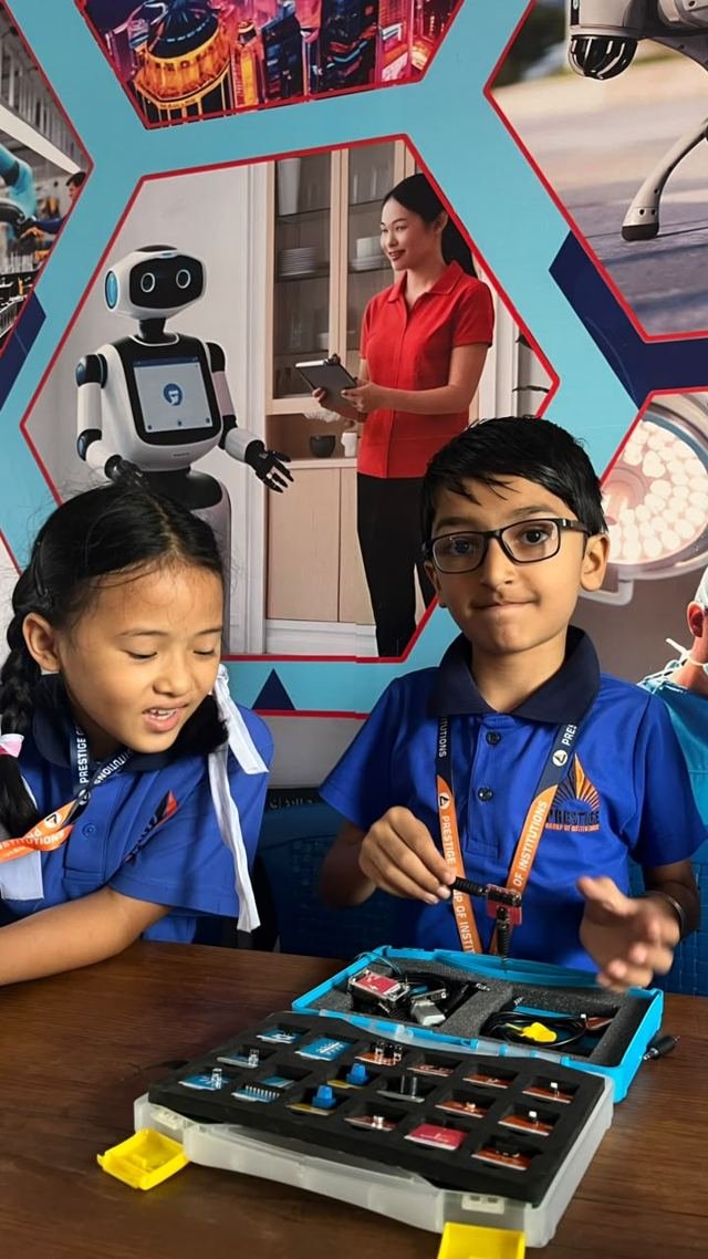 A smiling student and her classmate work on an electronics kit